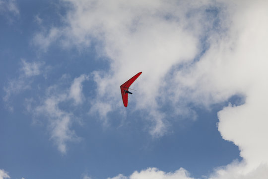 Red Hang glider, blue sky background with white clouds