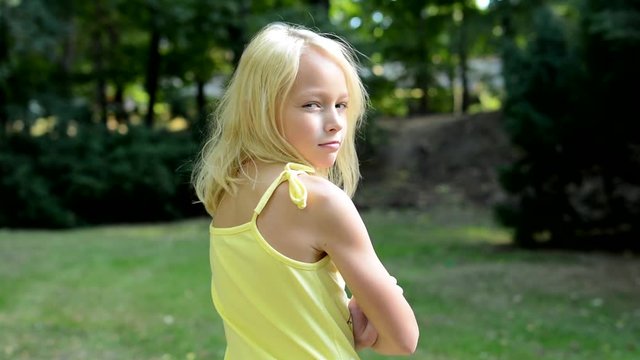 little cute girl offends in the park - look at her back - she turns to the camera - eye contact