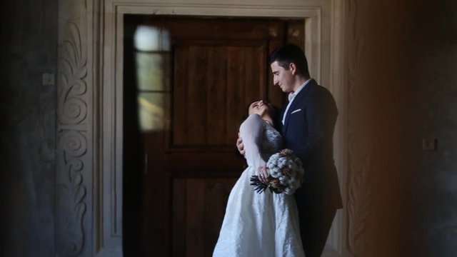 groom gently embraces the bride on a background of doors