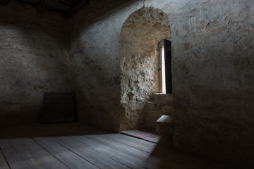 .Dark room with stone walls and window .
