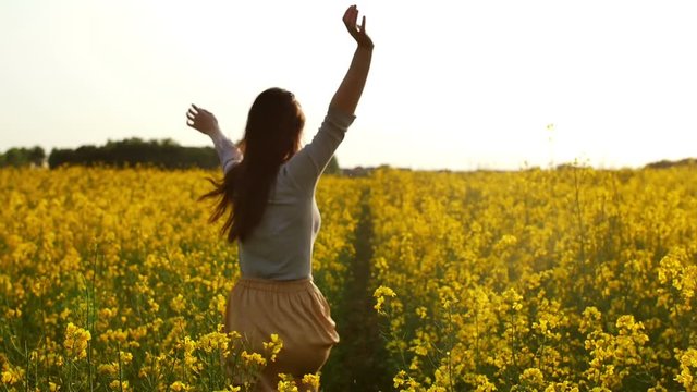 girl runs arms outstretched through a field slowmo