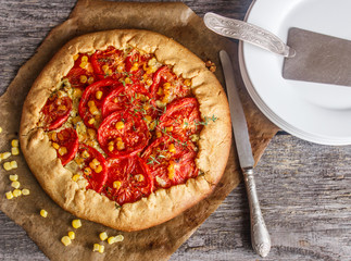 Homemade summer outdoor pie with tomatoes, corn and thyme. Galette with vegetables
