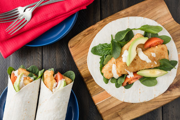 Crumbed fish fillet burrito with avocado and tomato