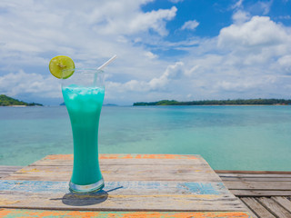Cocktail on the beach wood table by the sea ocean and blue sky and cloud.