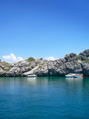 Fototapeta premium Rough coastline with clear blue sky and anchored boats.