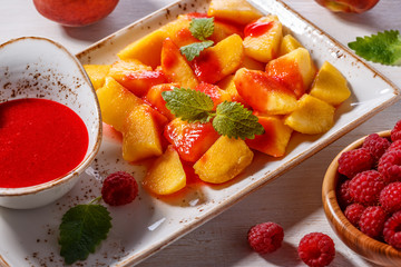 Plate of Sliced Peaches with Raspberry Sauce and Mint Leaf.