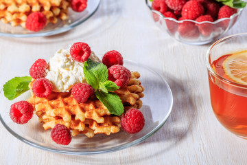 Waffles garnished with mascarpone and raspberries.