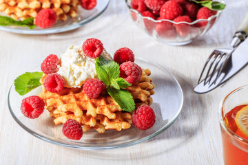 Waffles garnished with mascarpone and raspberries.