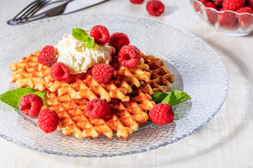 Waffles garnished with mascarpone and raspberries.
