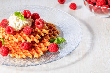 Waffles garnished with mascarpone and raspberries.