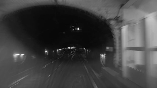 Black and white timelapse shot of a subway train moving in the dark tunnel, view from the cabin. Paris, France