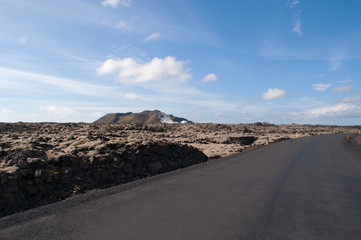 Islanda: una strada e il paesaggio islandese con campi di lava nella Penisola di Reykjanes il 16 agosto. In Islanda ci sono molti campi di lava di rocce nere coperte da un tappeto di muschio  