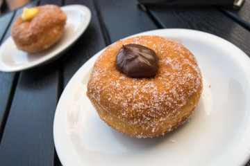 Bomboloni fritti ripieni di crema al cioccolato e crema pasticcera   sui piattini al bar 