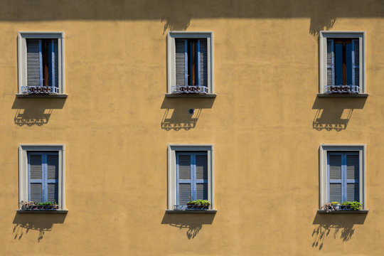 Finestre con persiane azzurre su una facciata giallo ocra  di uno stabile 
