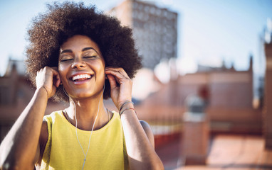 Young afro woman listen to music with headphones on the rooftop
