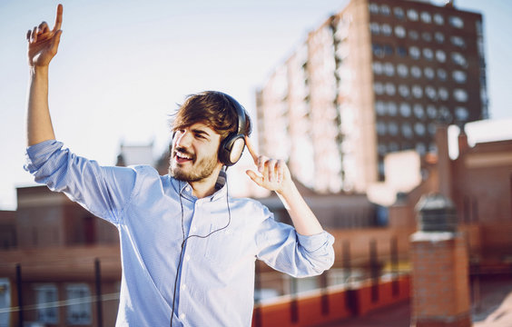 Young caucasian man listen to music with headphones on the rooft
