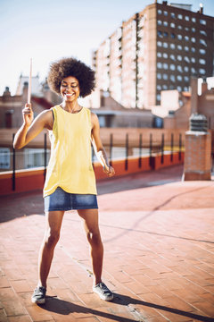 Young afro woman listen to music with headphones and imitating t