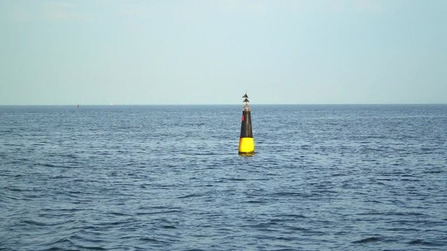 Yellow-black buoy in sea water as safety warning