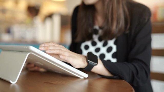 Woman with smart watch working on tablet