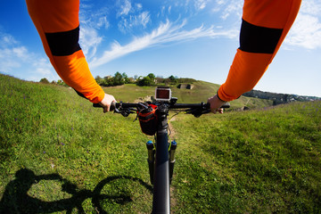 Hands in orange jacket holding handlebar of a bicycle