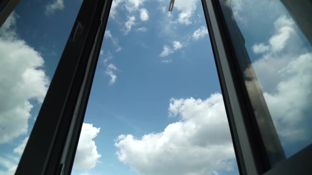 Flight of the Camera Through an Open Window into the Blue Sky With Clouds