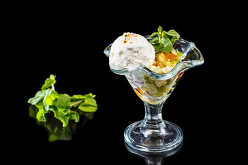 Ice cream with fruit and mint on black mirror background, isolat
