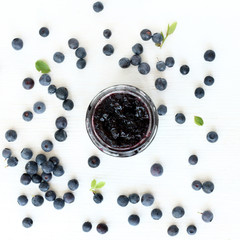sweet dessert of wild berries/ Open a jar of berry jam decorated with fresh berries and leaves forest blueberries top view