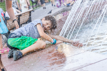 young happy child boy playing with water fountain, outdoor portr