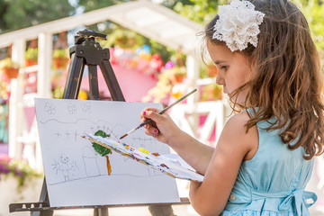 young happy child girl drawing a picture outdoors, kid painting