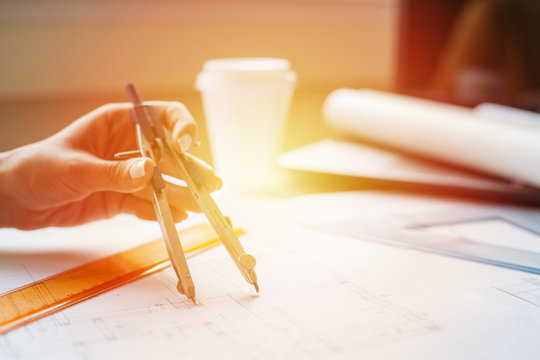 Woman hands drawing blueprints with a compass tool