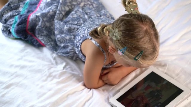 little cute girl plays a game on the tablet