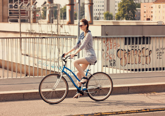 Fototapeta premium Beautiful woman riding bike in the city in Summer