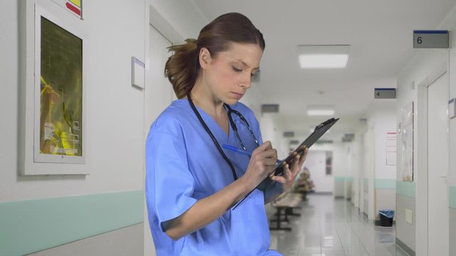 Nurse takes notes on clipboard outside room