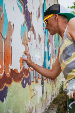 Senior Hipster Man Painting a Graffiti on a Wall with Spray