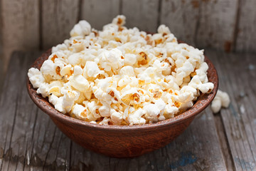 Fresh popcorn in bowl on white wooden table