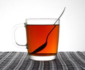 Tea glass cup with teaspoon on a tablecloth.