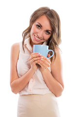 Young attractive brunette woman in a business suit drinking from blue cup, isolated on white background.