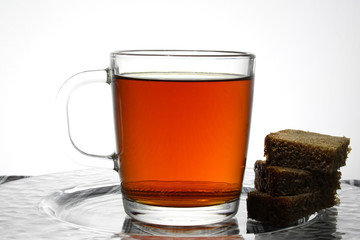 Tea glass cup with slices of rye bread on a tablecloth.