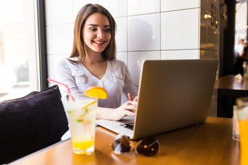 Casual girl using laptop and drink fresh at cafe