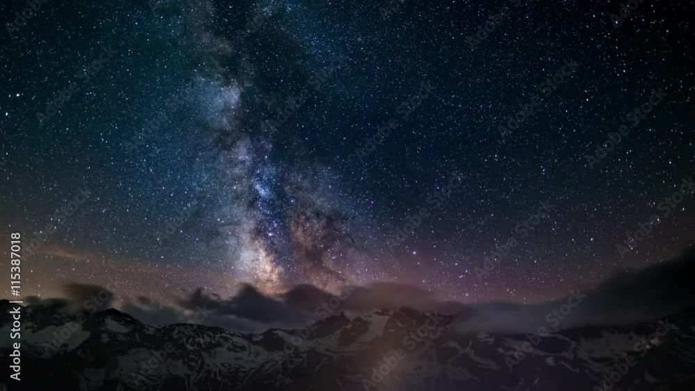 Wall mural the apparent rotation of an outstandingly bright milky way and the starry sky beyond snowcapped moun