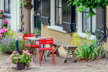 Fototapeta na wymiar Bright red chairs in front of a historic Dutch house