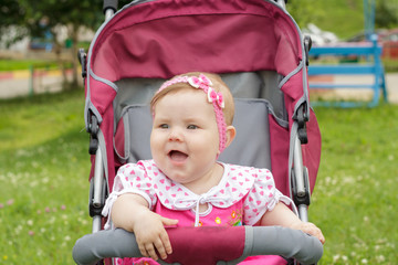 little newborn girl sitting in a baby carriage