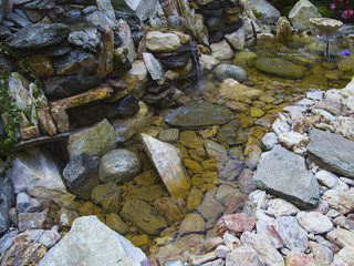.a fountain and a waterfall in the artificial pond with rocks in the landscape park