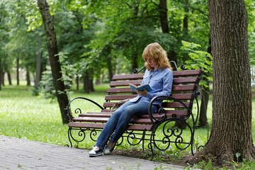 Young woman on a bench reading a book