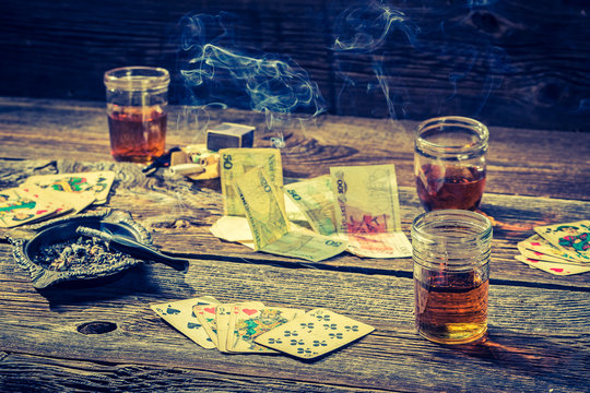Vodka, cigarettes and cards on vintage table for illegal poker