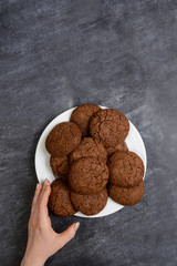 Picture of hands holding chocolate cookies over wooden background
