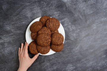Picture of hands holding chocolate cookies over wooden background