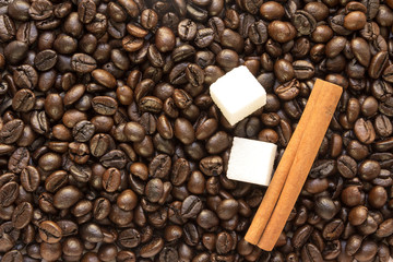 pieces of white sugar and cinnamon sticks on the coffee bean Brown background