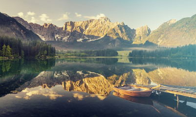 łódki zacumowane przy drewnianym pomoście nad pięknym,górskim jeziorem,kolorystyka retro