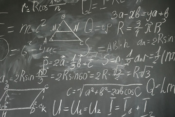 with math formulas written in white chalk on black board background